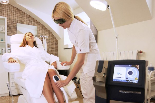 косметолог проводит лазерную эпиляцию в клинике