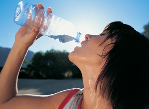 Женщина пьет воду от перегрева